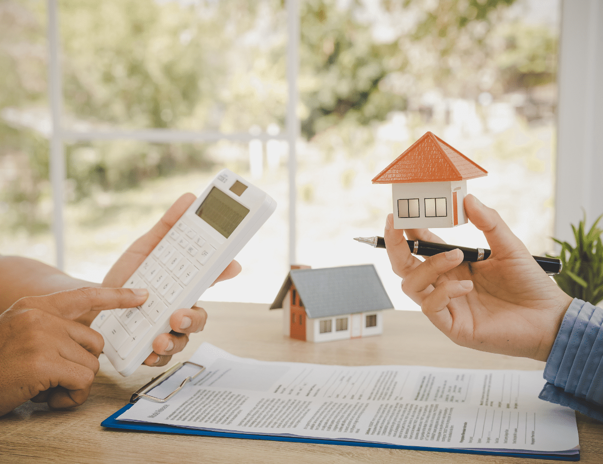 Photo of a someone holding a calculator and a miniature house