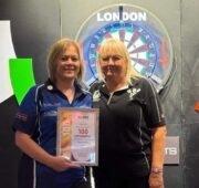 Nina receives award for 100 darts appearances, holding framed certificate.