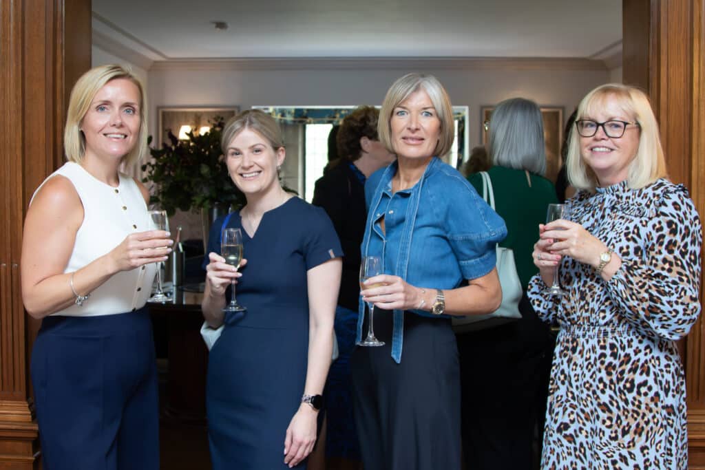 Four women at a networking event holding drinks.