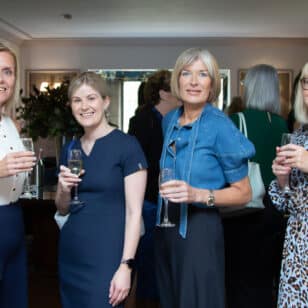 Four women at a networking event holding drinks.