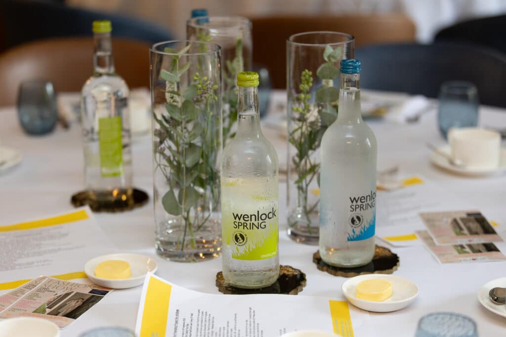 Wenlock Spring water bottles and floral arrangements on a table at a networking lunch.