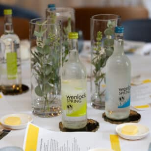 Wenlock Spring water bottles and floral arrangements on a table at a networking lunch.