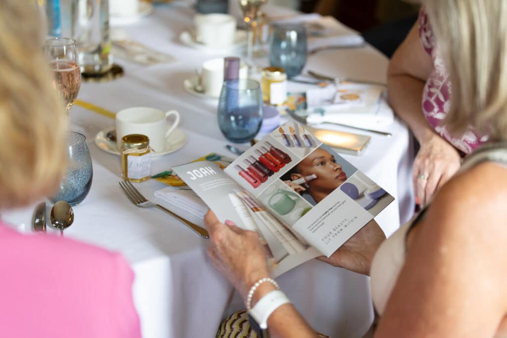 Ladies at networking lunch read JOAH beauty brochure