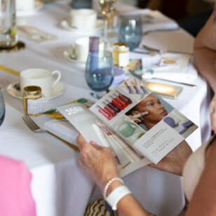 Ladies at networking lunch read JOAH beauty brochure