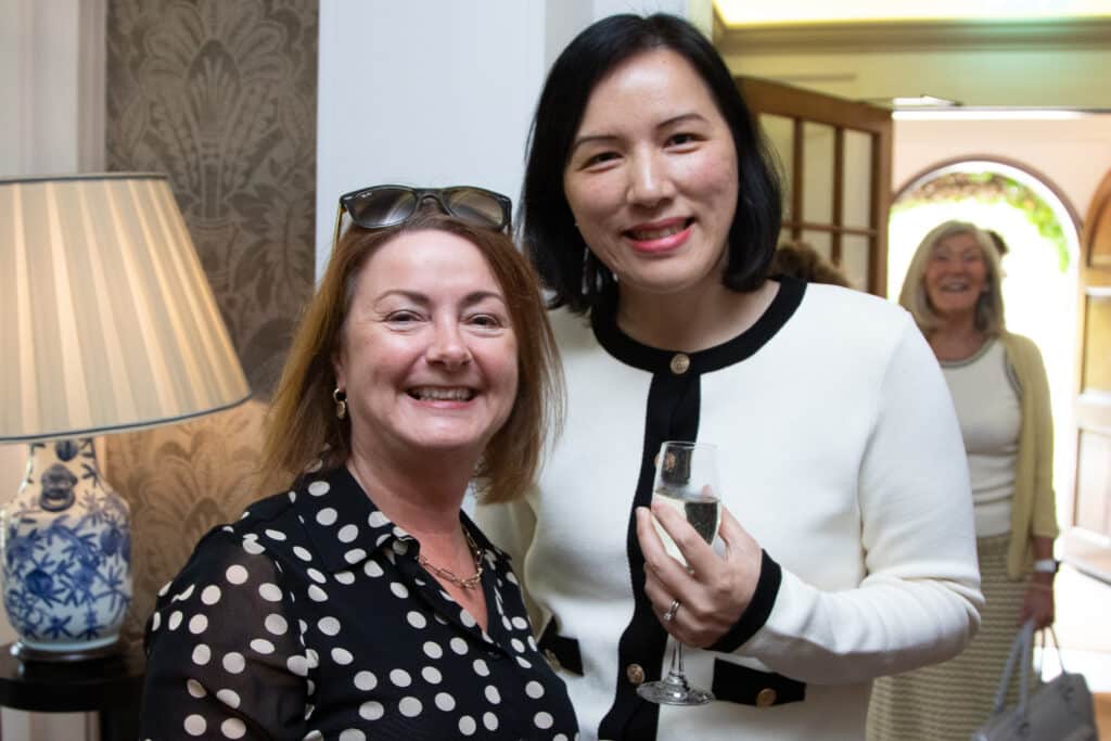 Ladies at a networking lunch: Two women smiling at the camera, one holding a glass.