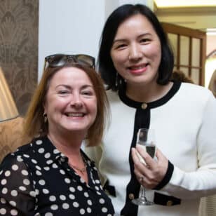 Ladies at a networking lunch: Two women smiling at the camera, one holding a glass.