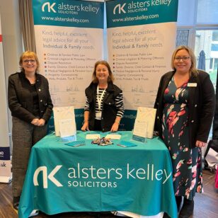 Three women at Alsters Kelley Solicitors table at Banbury Chamber of Commerce Expo