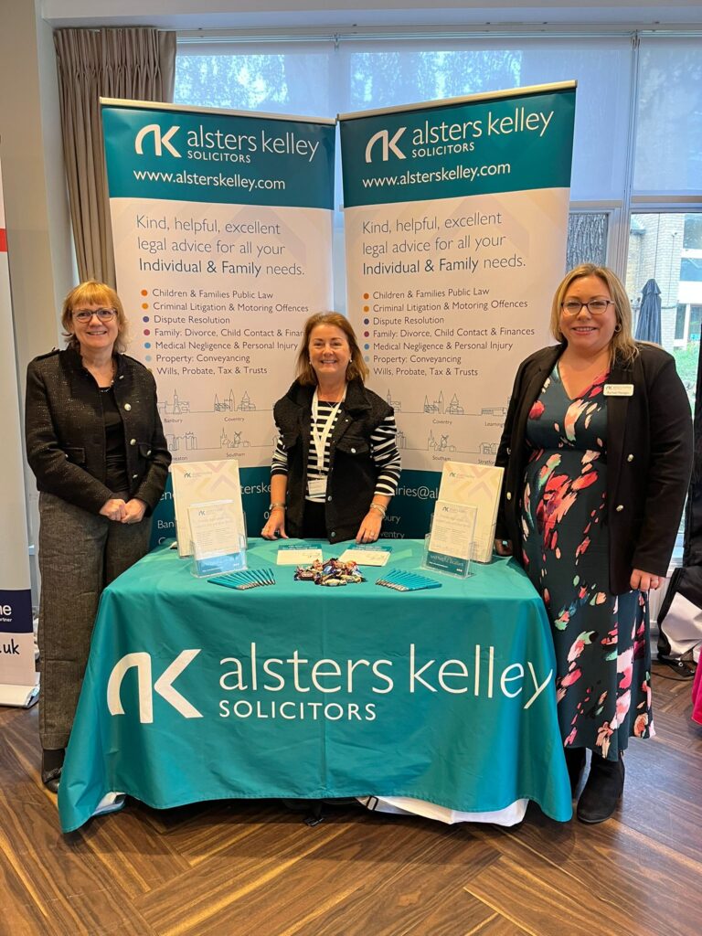 Three women at Alsters Kelley Solicitors table at Banbury Chamber of Commerce Expo