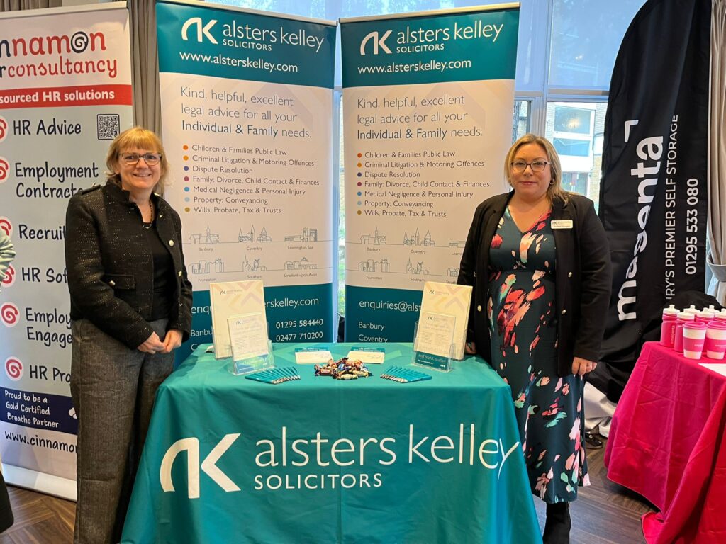 Two women at Banbury Chamber of Commerce Expo, standing behind an Alsters Kelley Solicitors banner