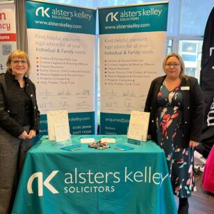 Two women at Banbury Chamber of Commerce Expo, standing behind an Alsters Kelley Solicitors banner