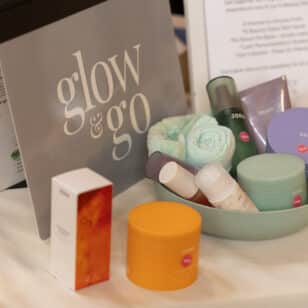 Table with glow & go skincare products in a green bowl, box, and towels