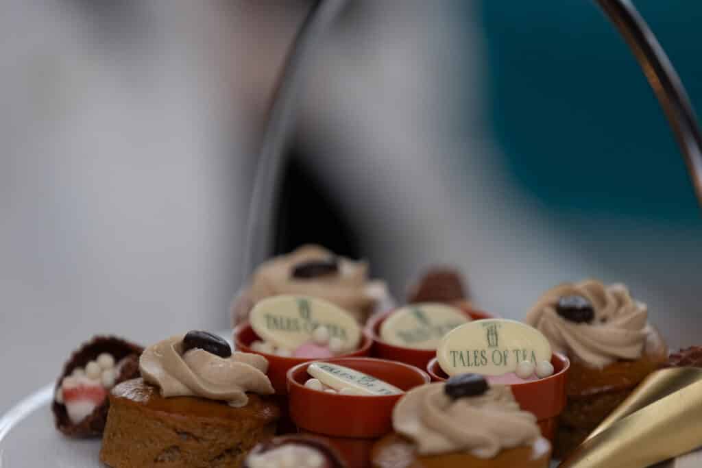 Assorted mini cakes on a plate, each topped with cream and chocolate.