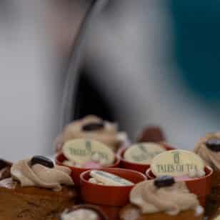 Assorted mini cakes on a plate, each topped with cream and chocolate.