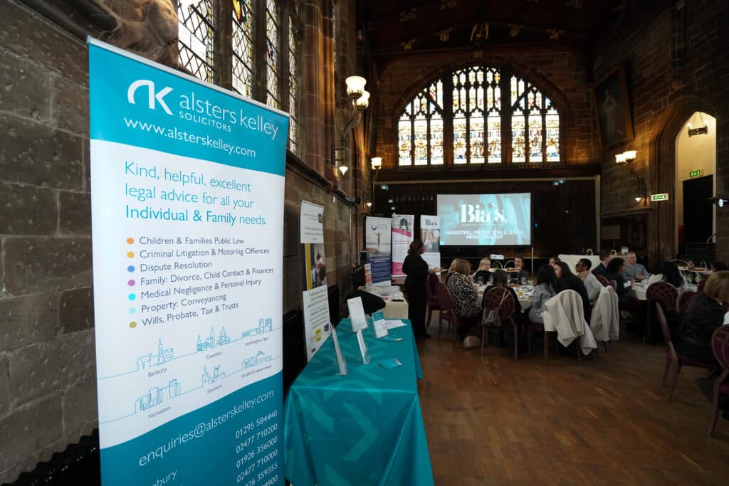 Lawyers at Alsters Kelly networking event, seated guests, and informational banners