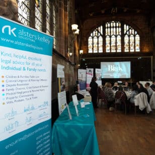 Lawyers at Alsters Kelly networking event, seated guests, and informational banners