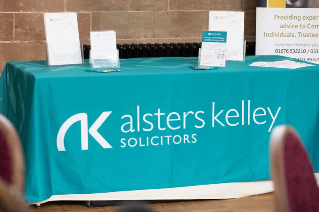 Blue table covered in teal cloth with Alsters Kelley Solicitors logo