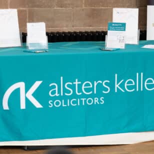 Blue table covered in teal cloth with Alsters Kelley Solicitors logo