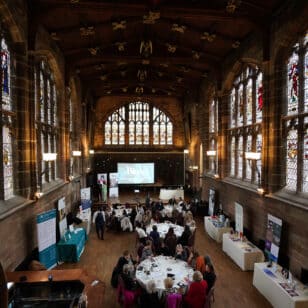 Conference attendees at Ladies First Networking event in a hall with stained glass windows