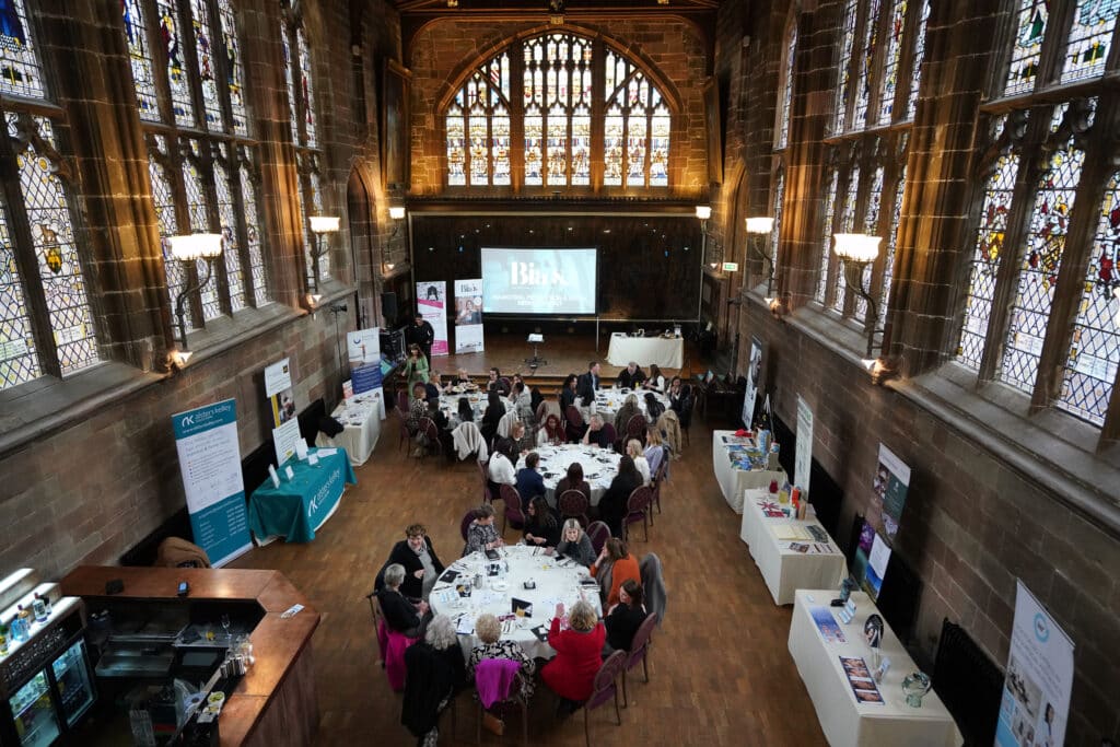 Networking event with women seated at round tables in a historic hall