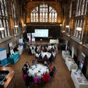 Networking event with women seated at round tables in a historic hall