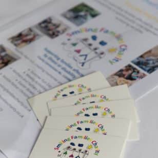 Smiling Families Charity logo and materials on a table at a Ladies First Lunch event.