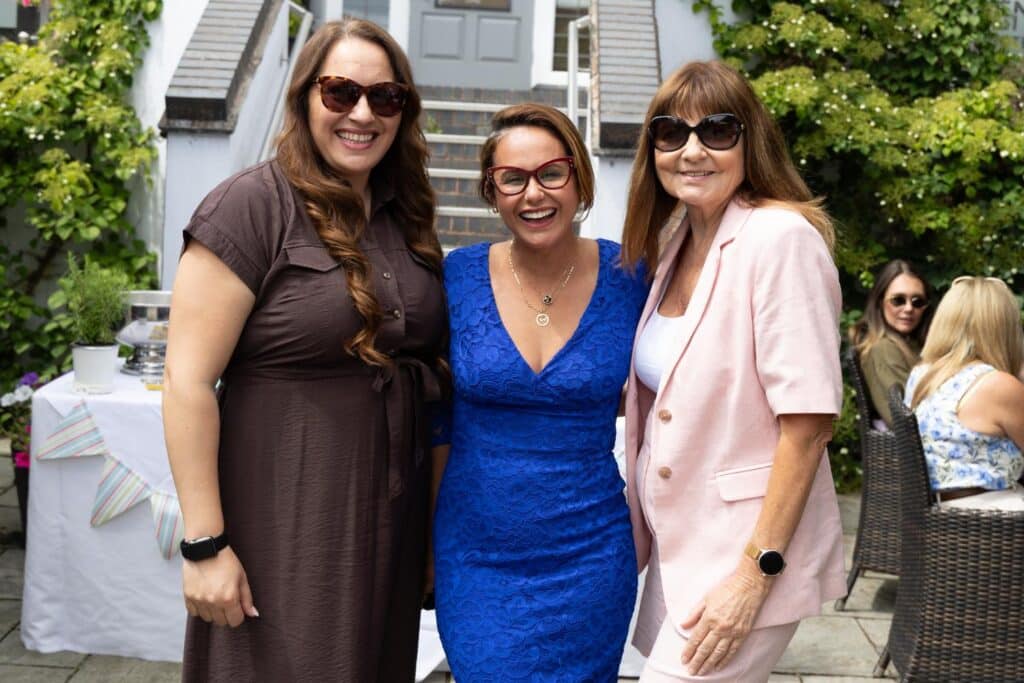 Three smiling women in casual outdoor attire pose for a photo.