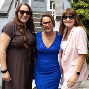 Three smiling women in casual outdoor attire pose for a photo.